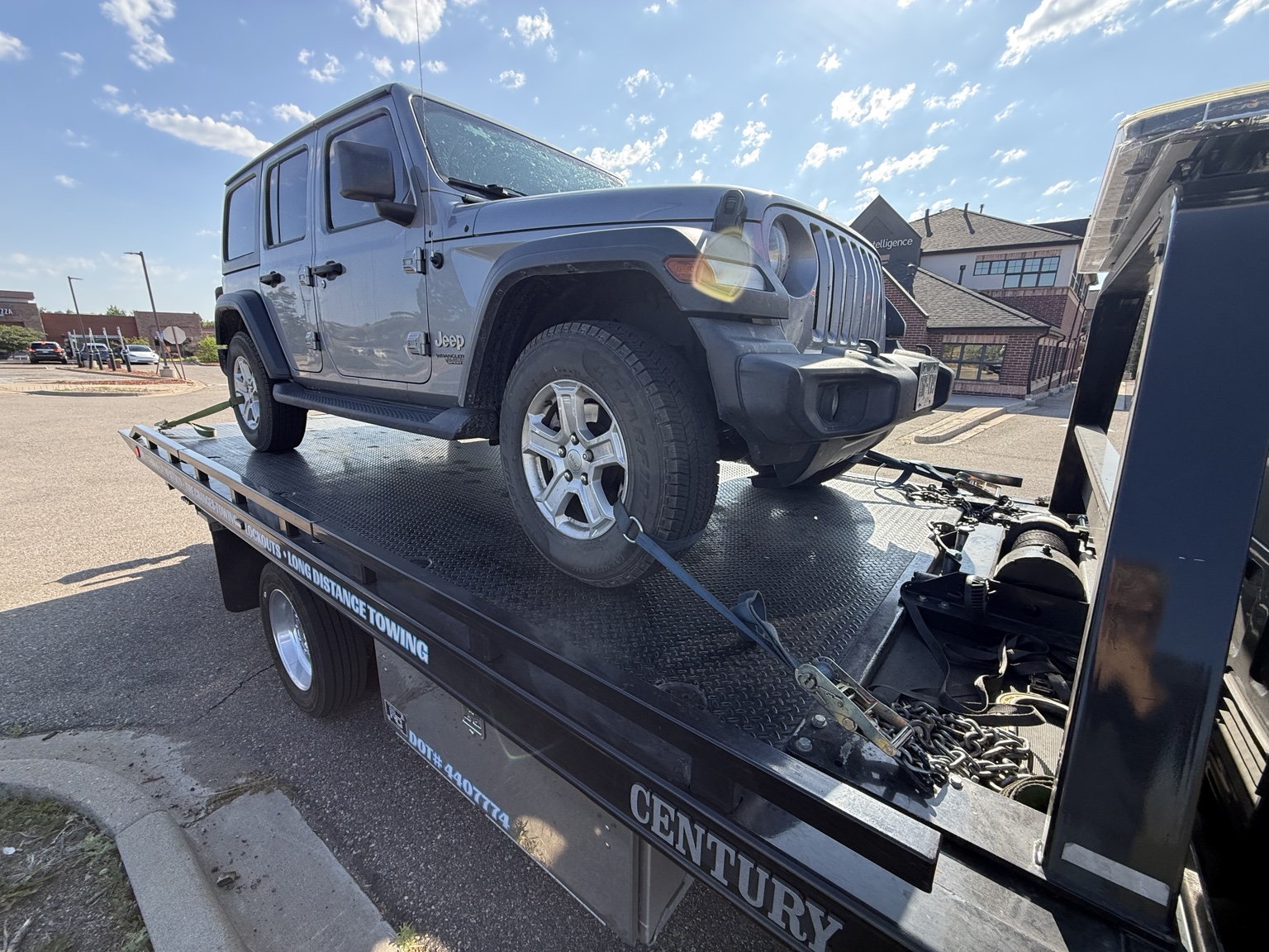 Gray Jeep on a flatbed trailer with ramp down for off-road vehicle transport