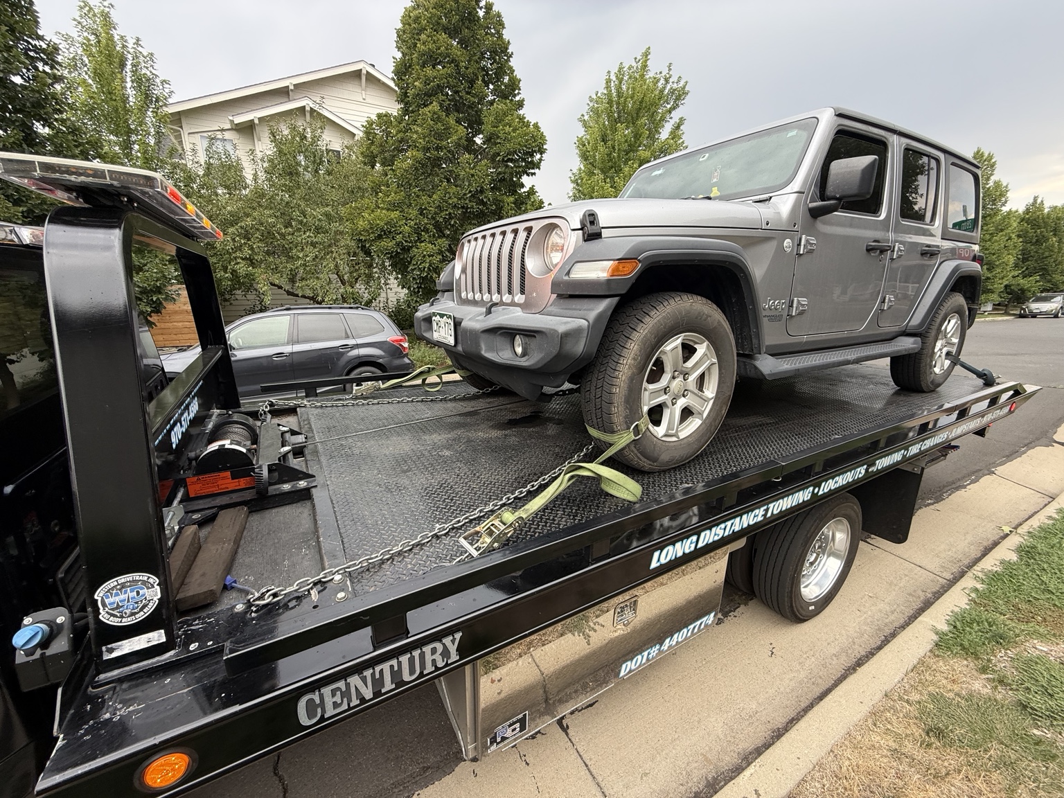 Gray Jeep secured on a heavy-duty tow trailer for off-road vehicle transport