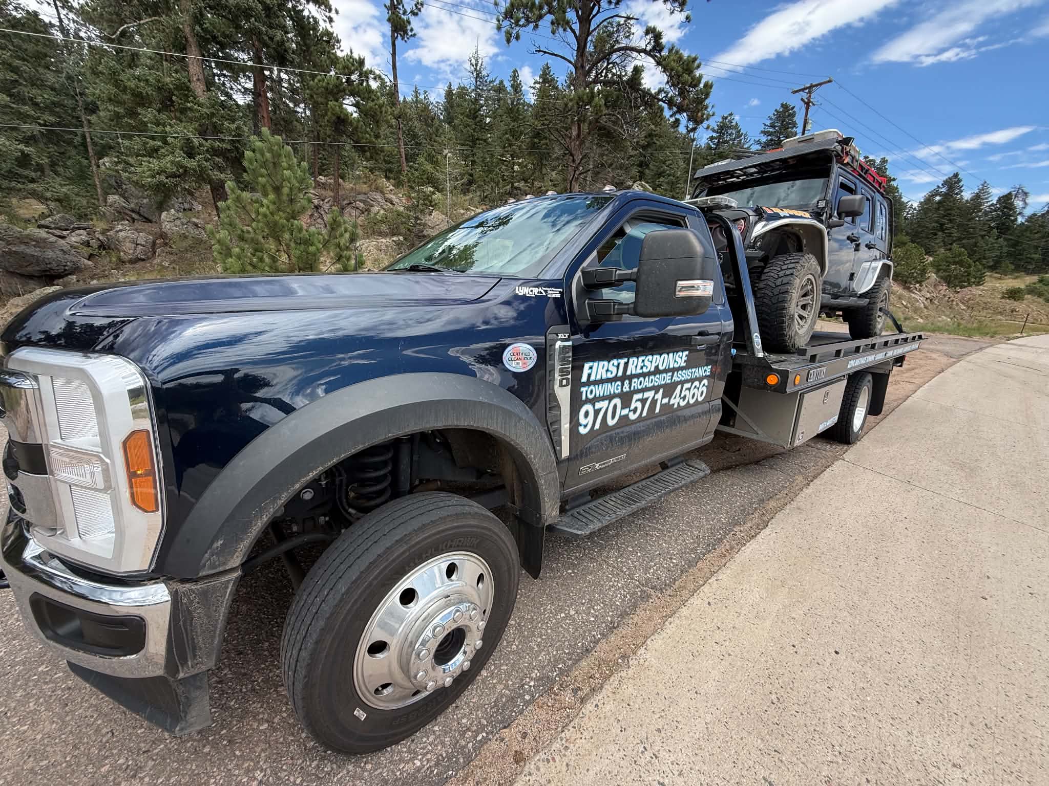 First Response Towing flatbed carrying an off-road Jeep on a mountain roadside