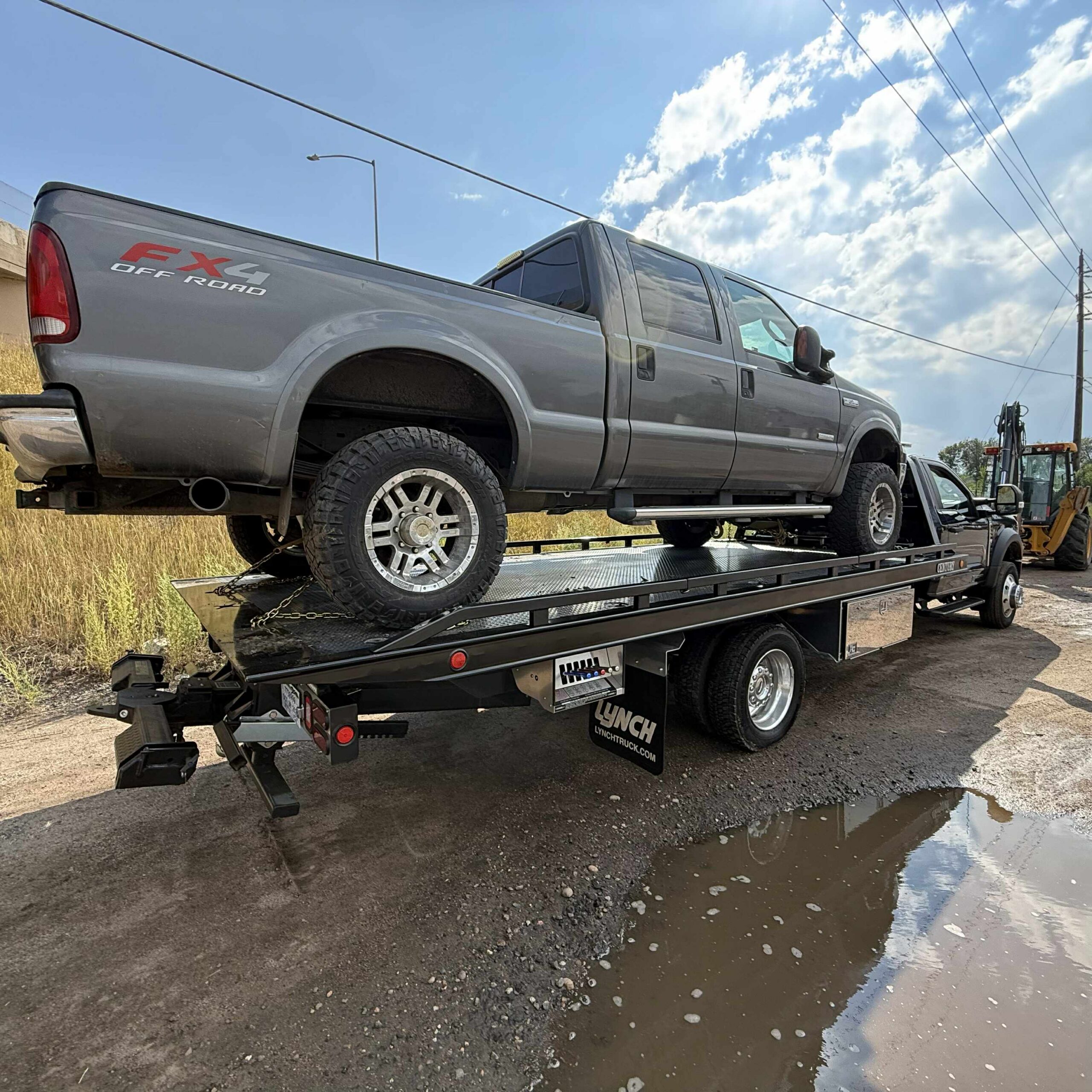 Lifted gray pickup truck secured on a flatbed trailer