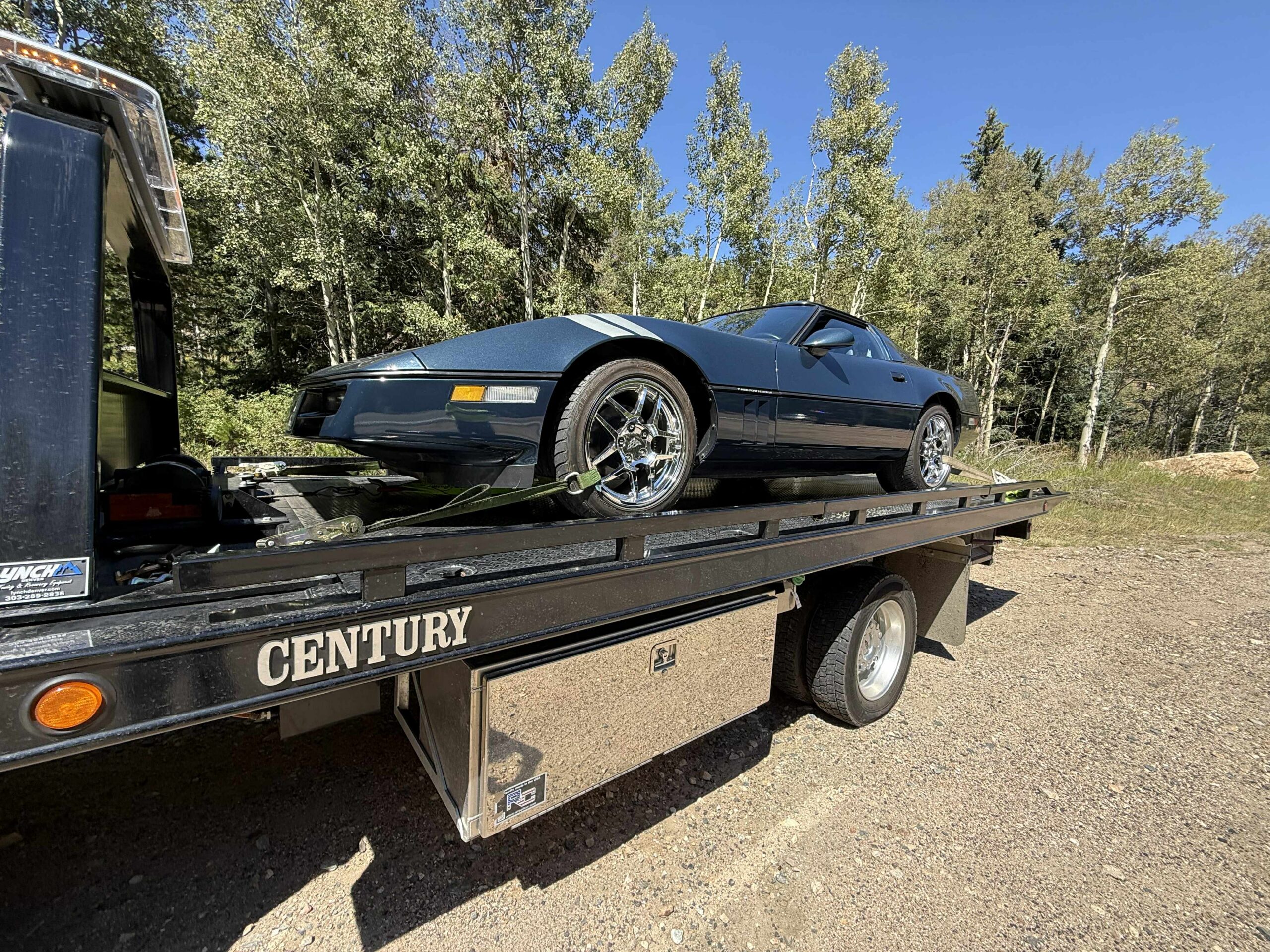 Dark blue classic sports car loaded on a flatbed trailer
