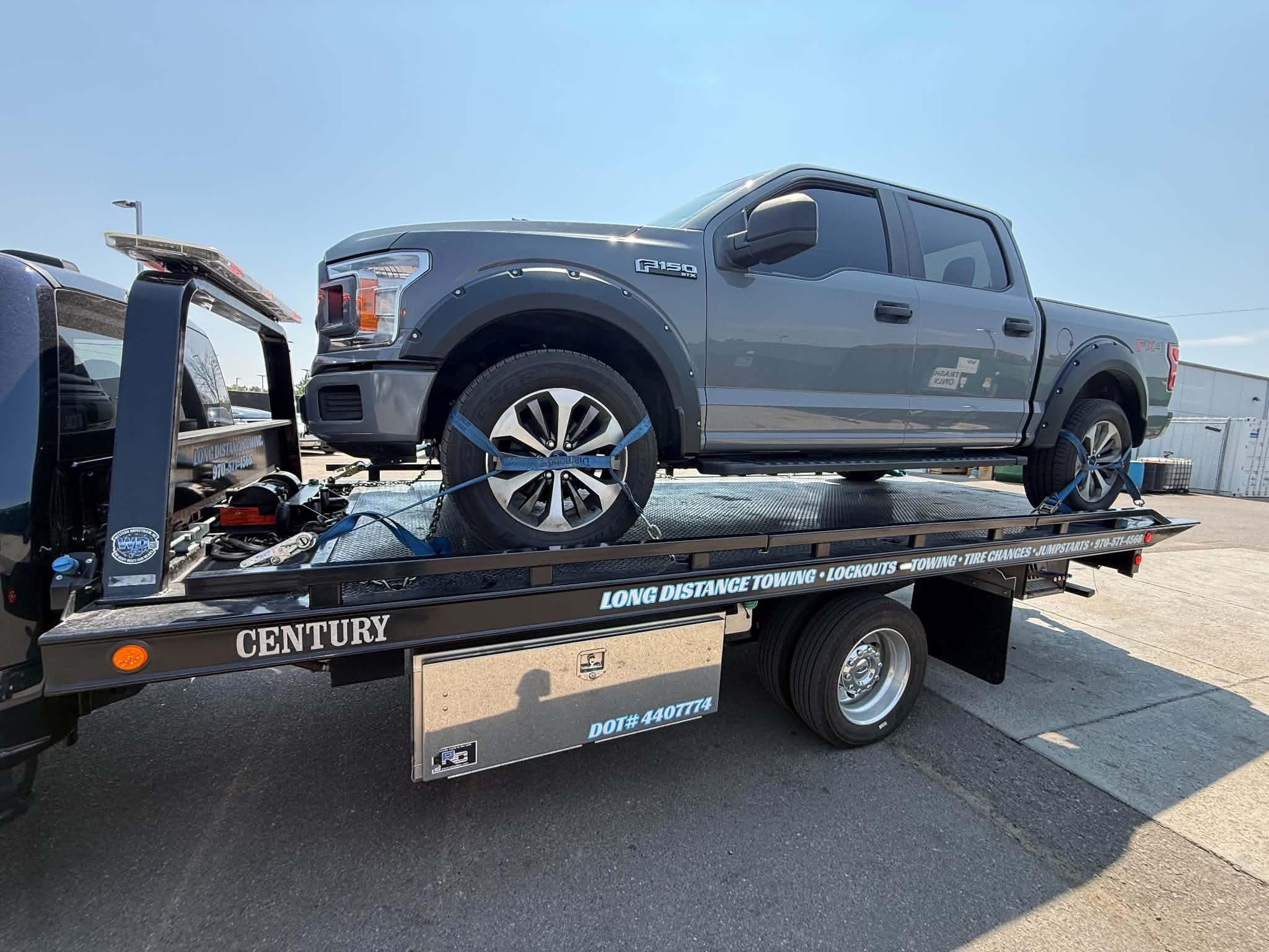 Silver Ford F-150 secured on a flatbed tow truck