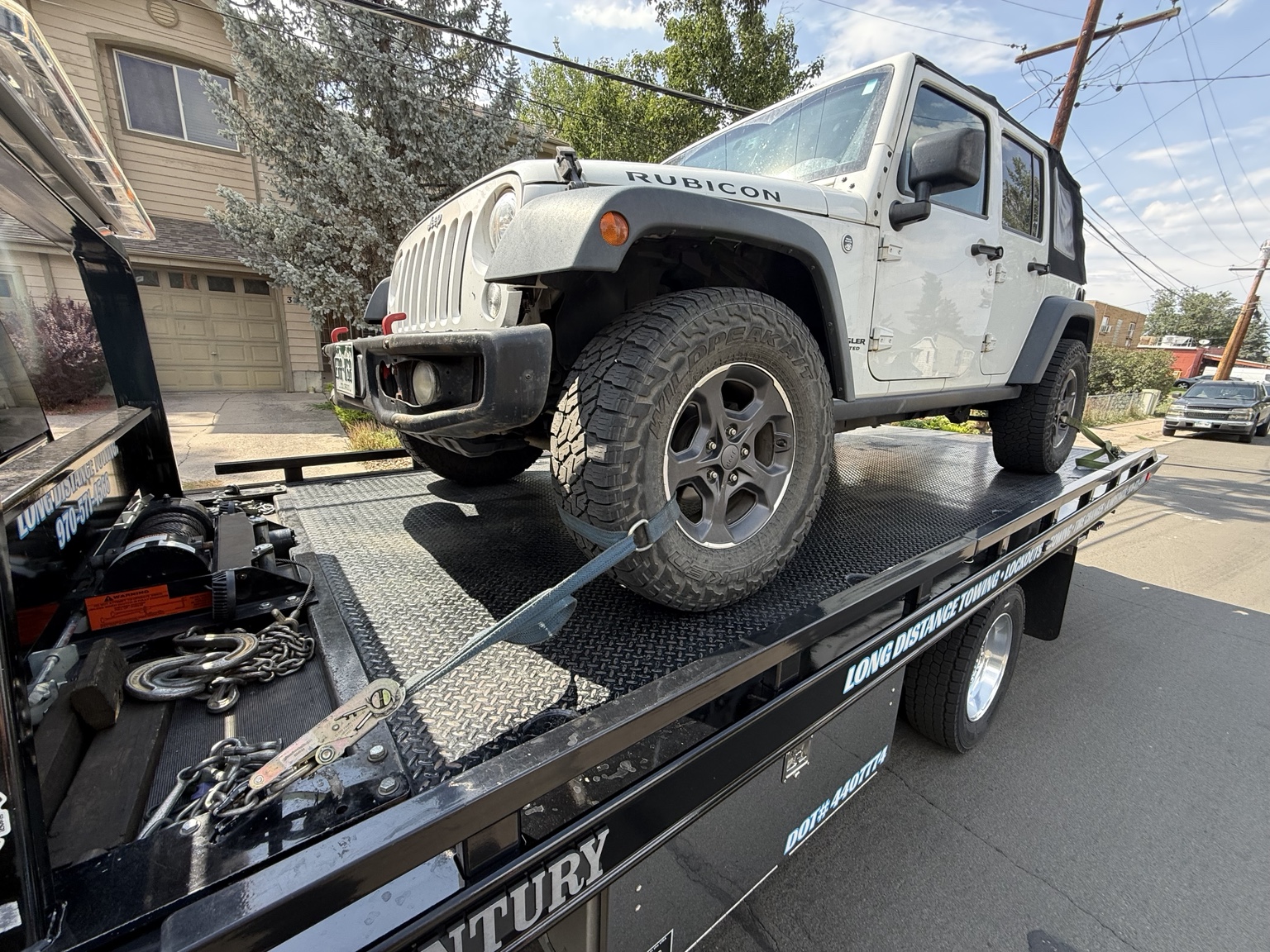 White Jeep Rubicon loaded on a black tow trailer for off-road vehicle towing