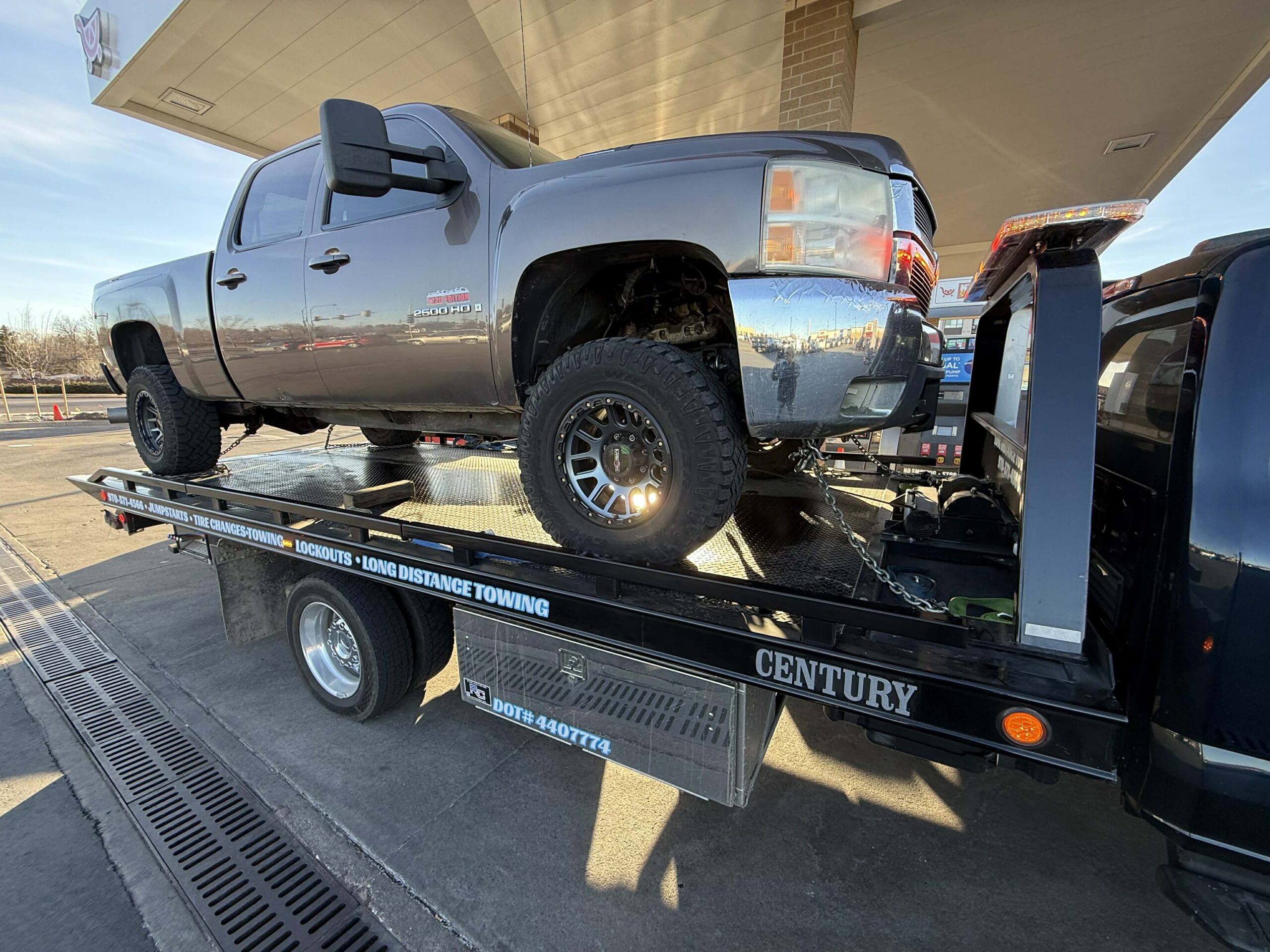 Gray pickup truck being towed on a black flatbed trailer
