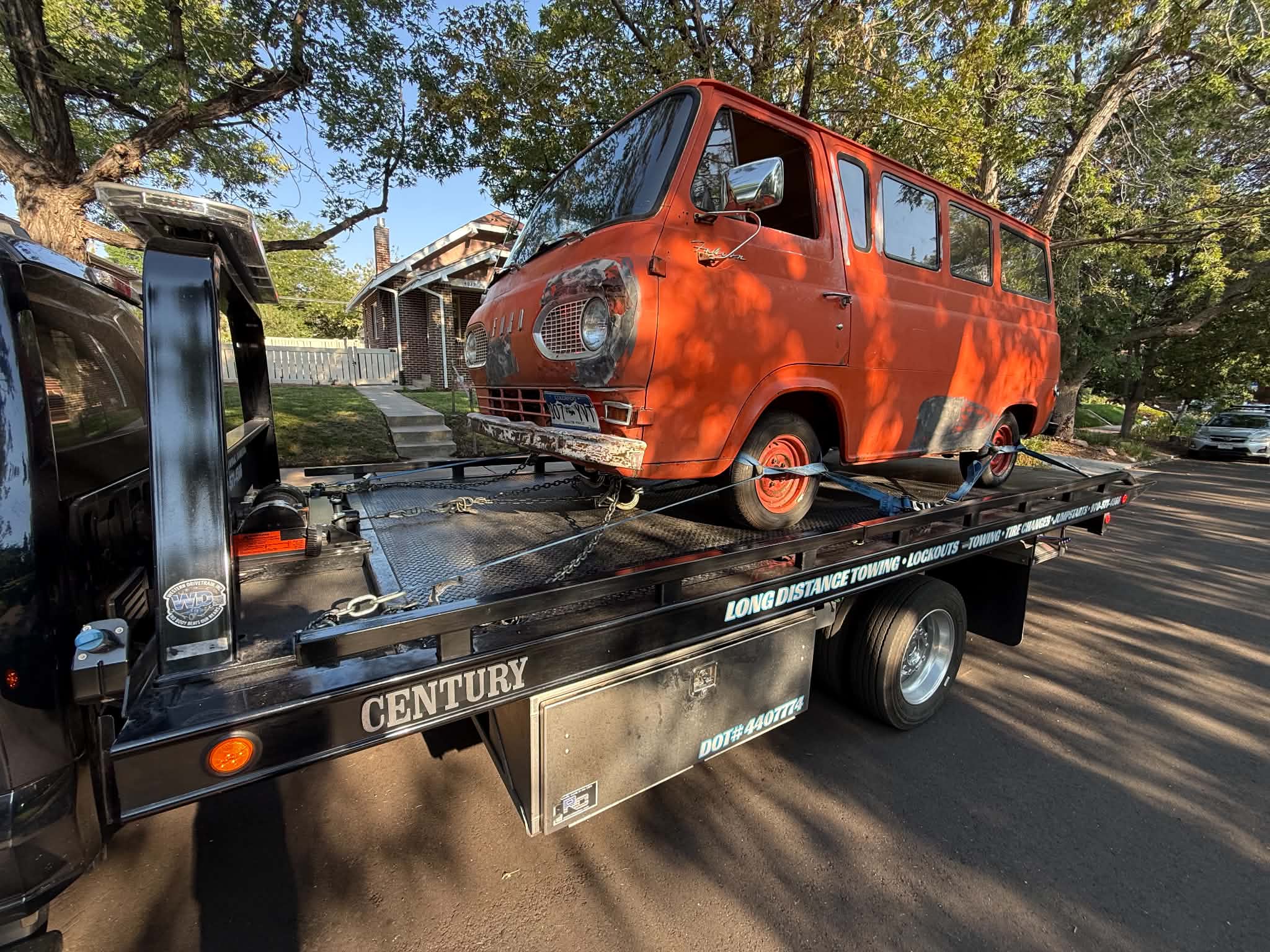 Bright orange vintage van loaded on a tow trailer